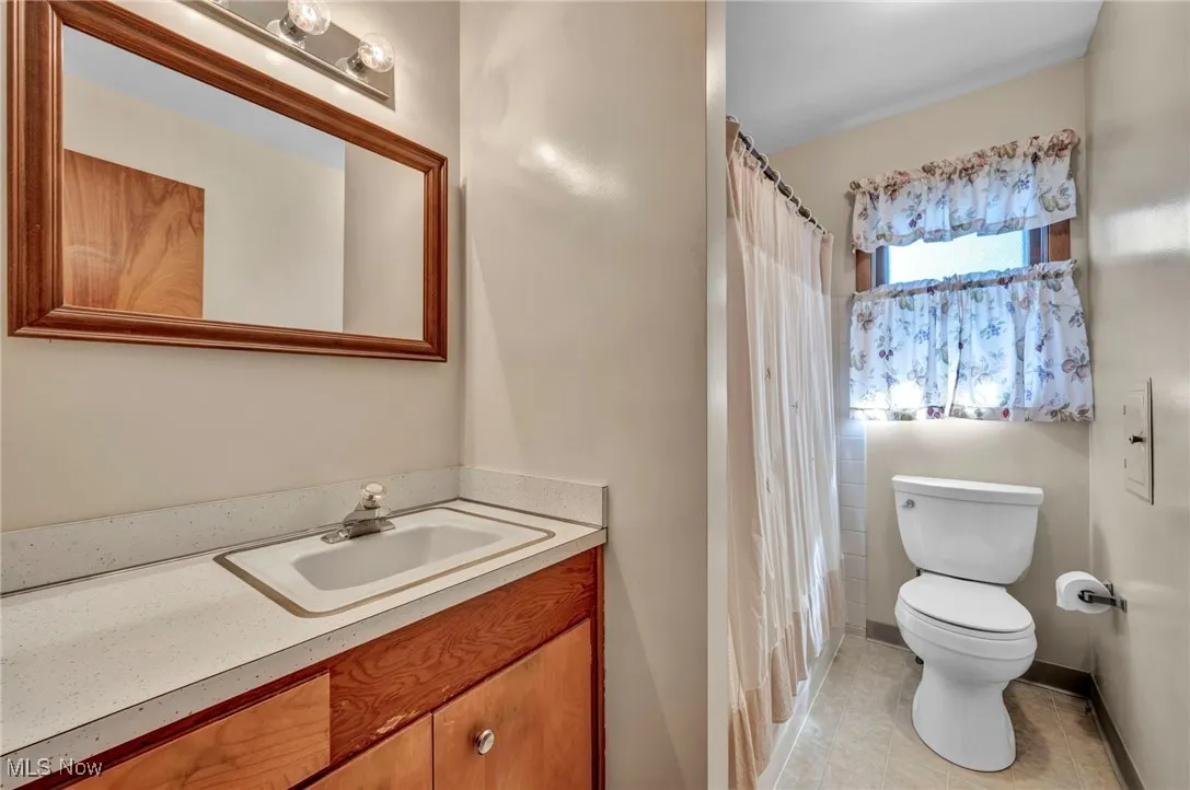 Bathroom with vanity, light tile patterned flooring, and curtained shower