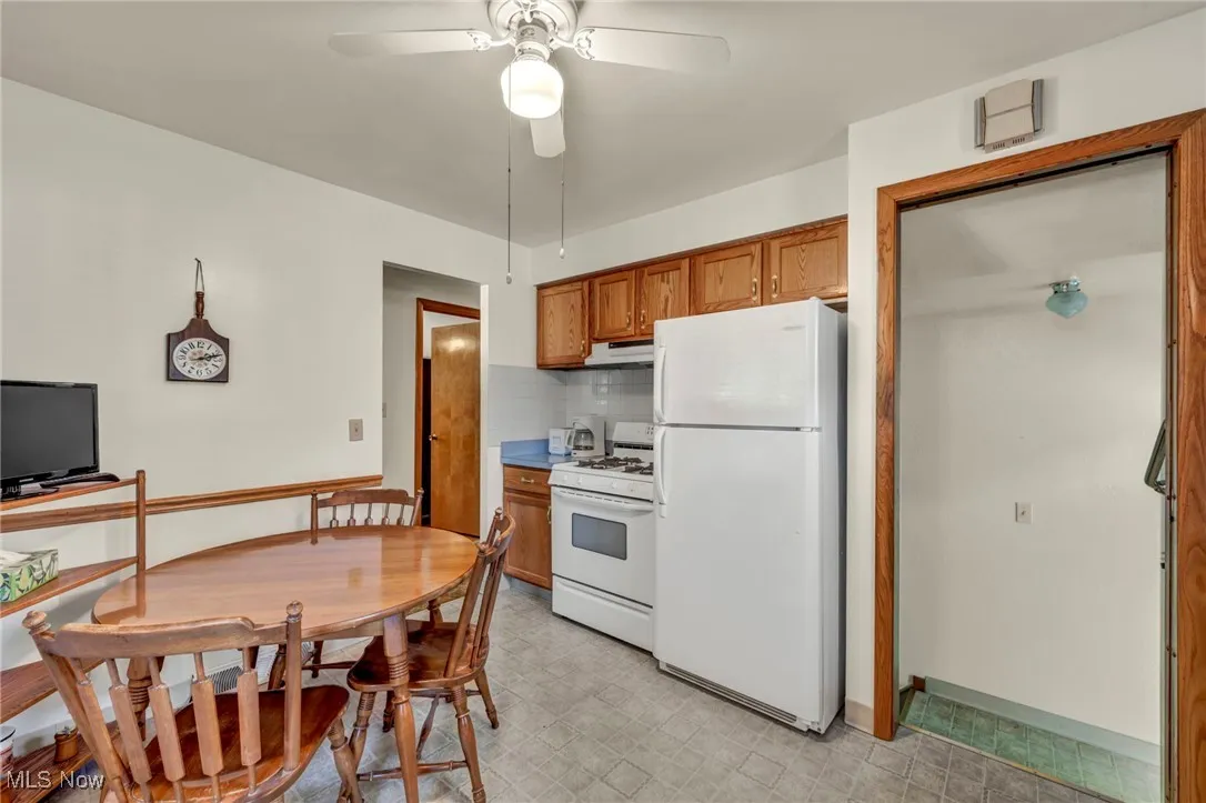 Kitchen with brown cabinets, white appliances, decorative backsplash, a ceiling fan, and light countertops