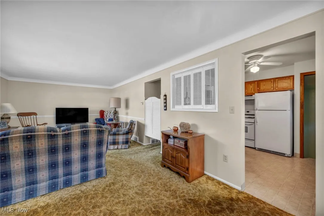 Living area with light colored carpet and a ceiling fan
