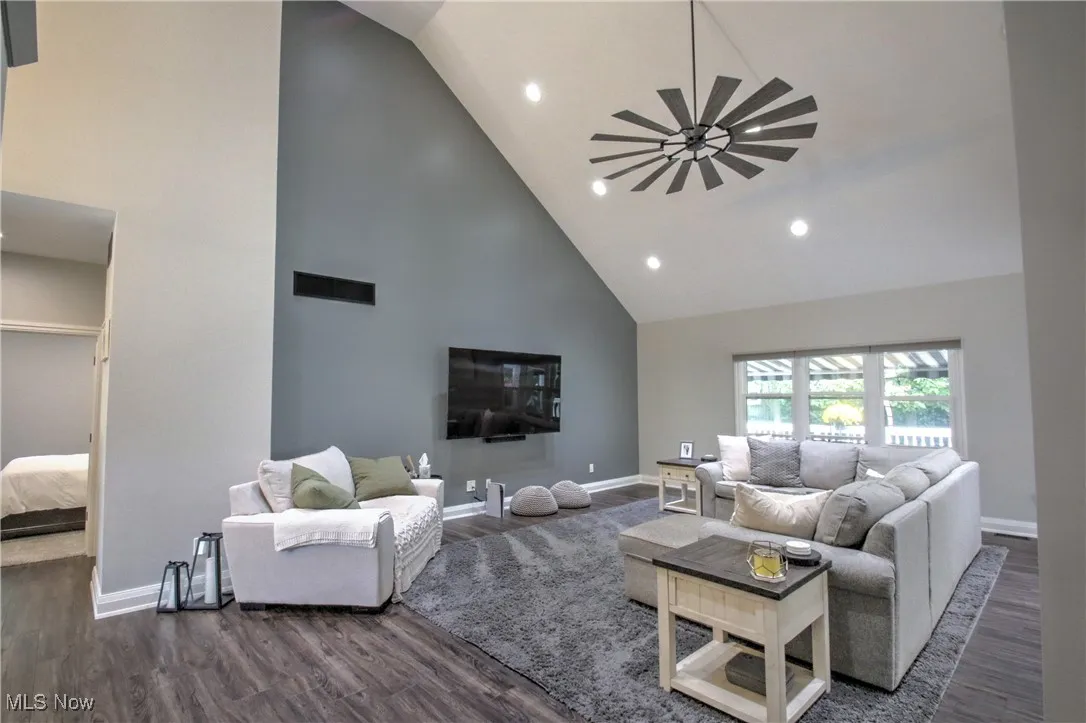 Living room with high vaulted ceiling, dark wood-style flooring, recessed lighting, and a ceiling fan