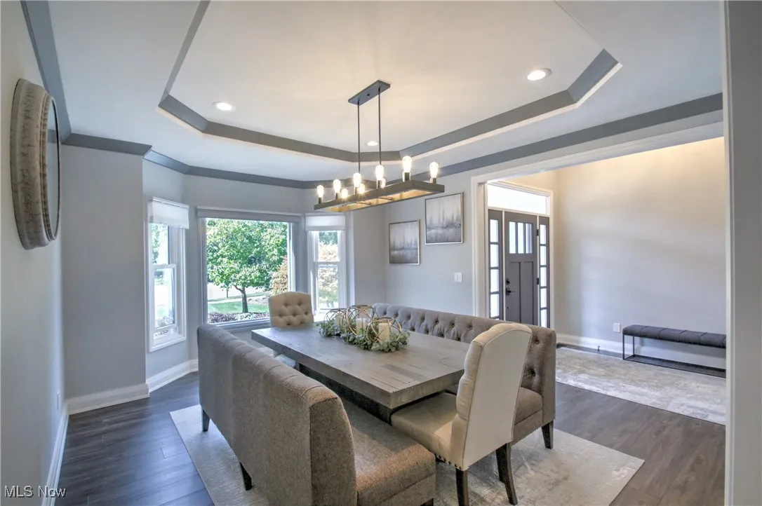 Dining area featuring a tray ceiling, dark wood-style floors, recessed lighting, and a chandelier