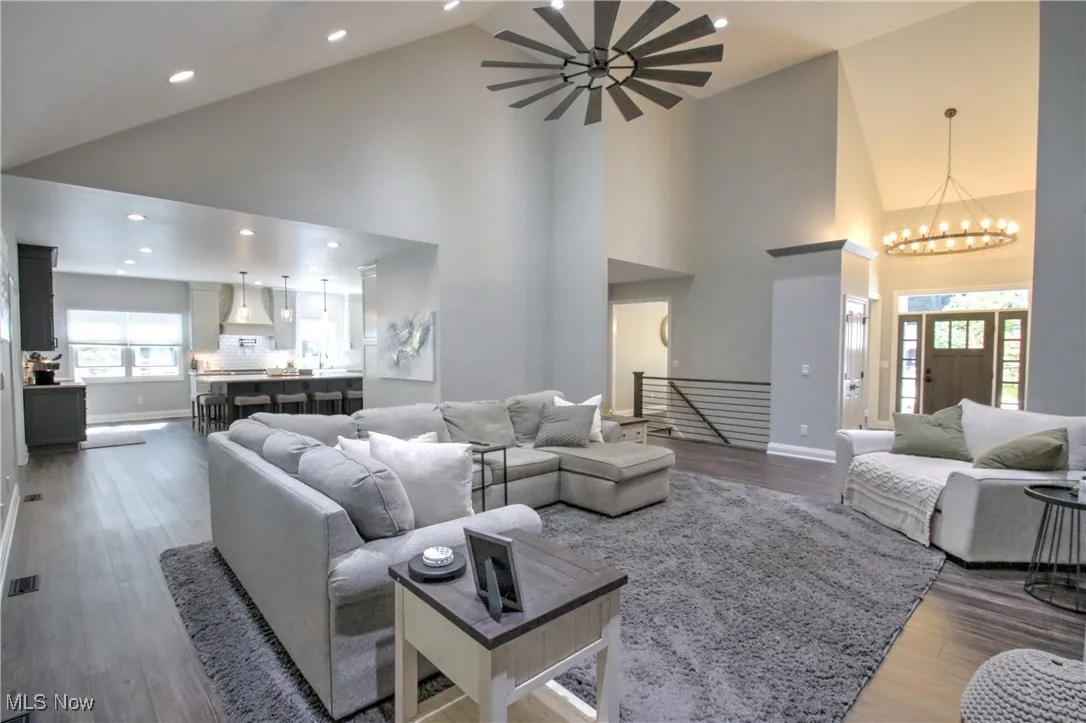 Living area featuring plenty of natural light, dark wood finished floors, high vaulted ceiling, recessed lighting, and a chandelier