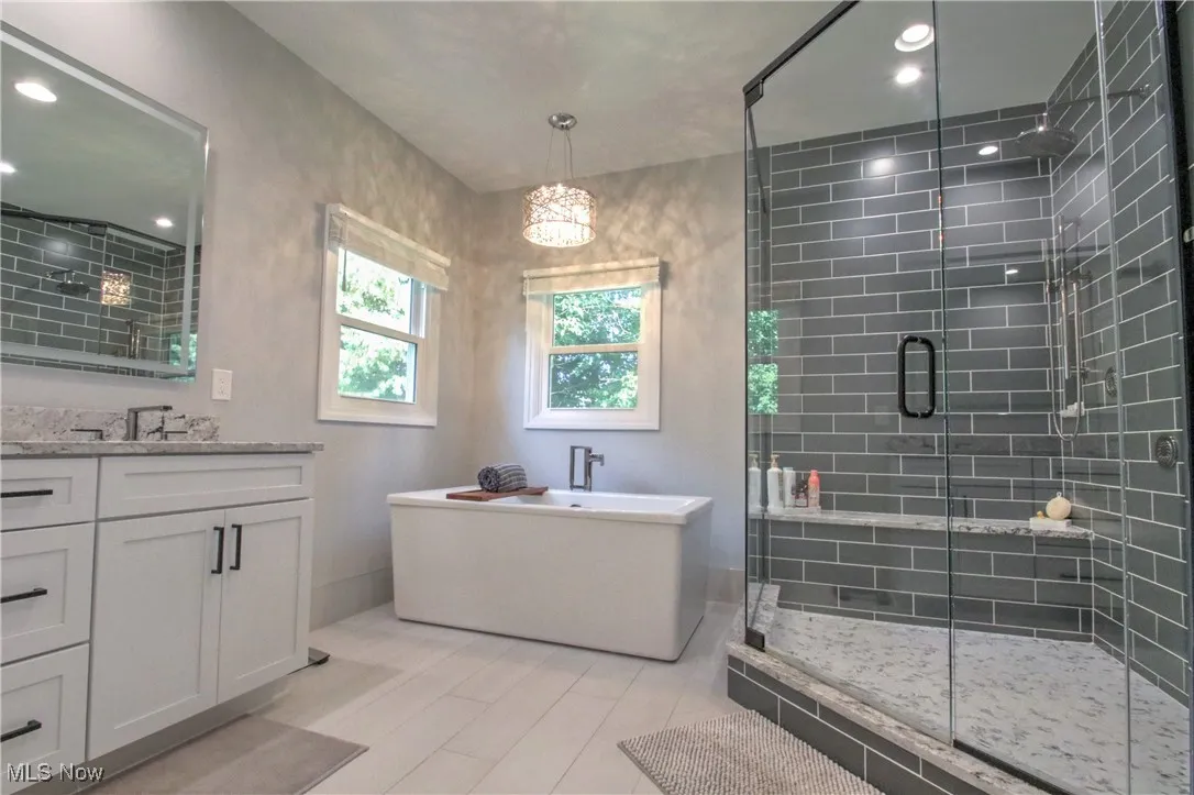 Master Bathroom with vanity, a freestanding bath, recessed lighting, and a shower stall