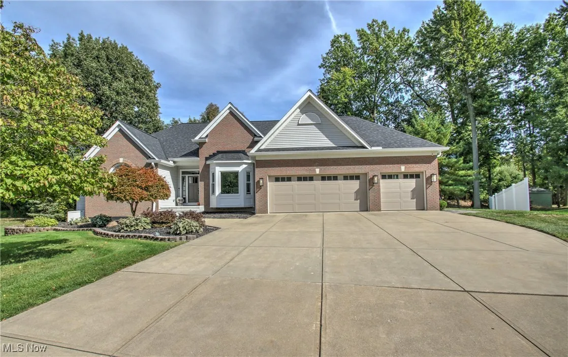 View of front of home featuring brick siding, a front yard, a garage, and driveway