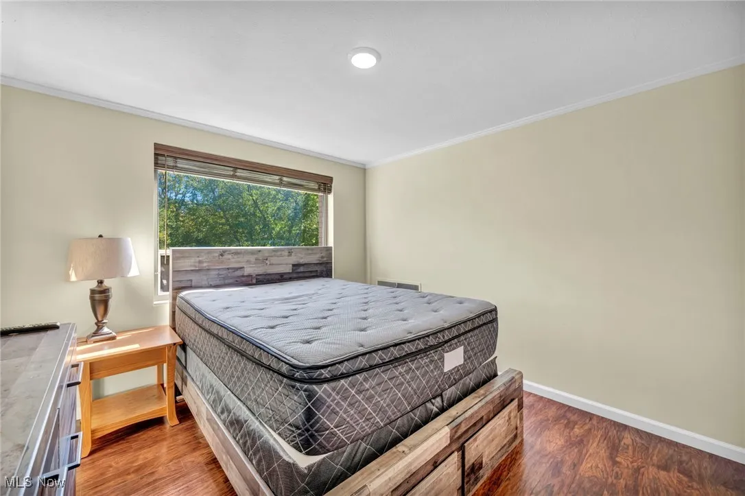 Bedroom with crown molding and wood finished floors