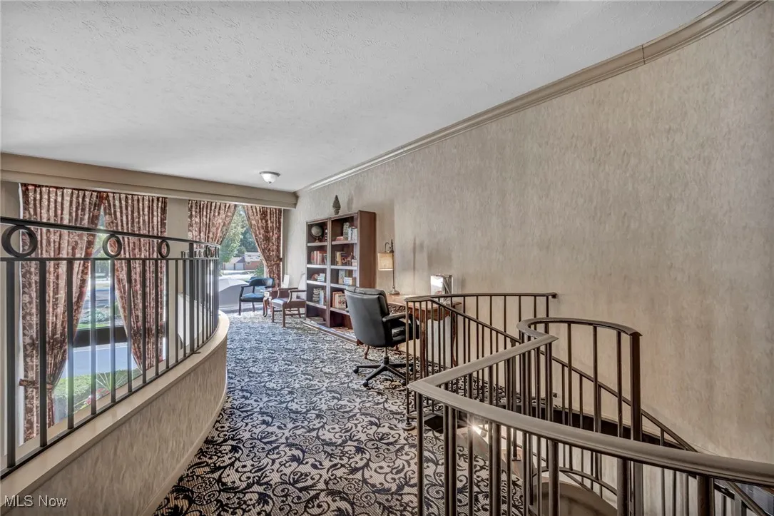 Carpeted office with crown molding, wallpapered walls, and a textured ceiling