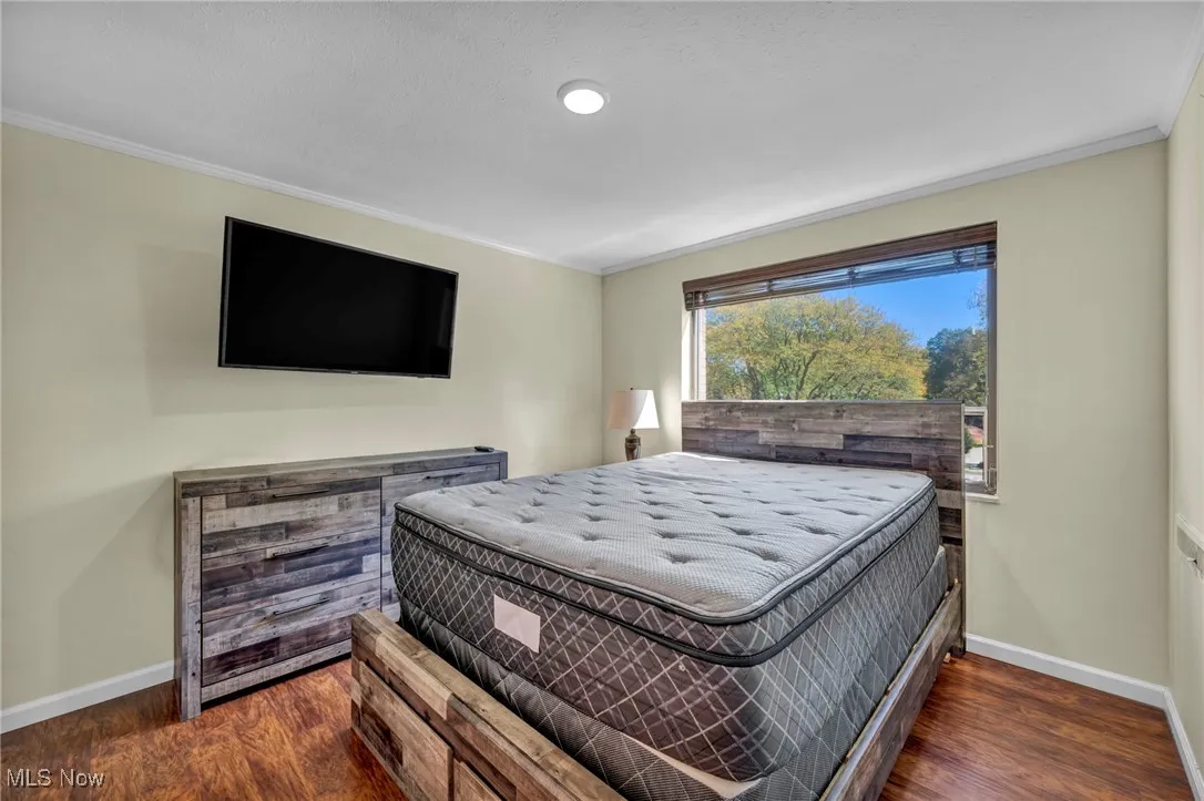 Bedroom featuring dark wood-style flooring and crown molding