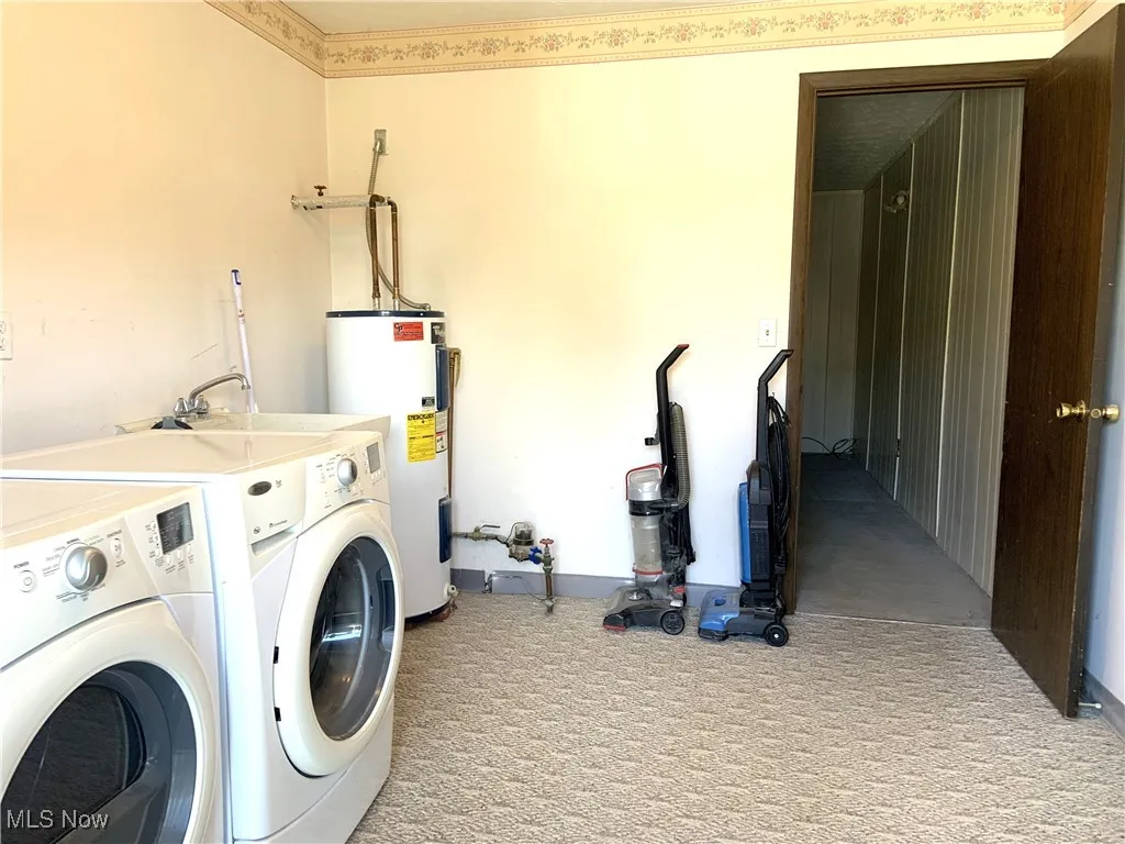 Washroom with carpet flooring, washing machine and dryer, and electric water heater