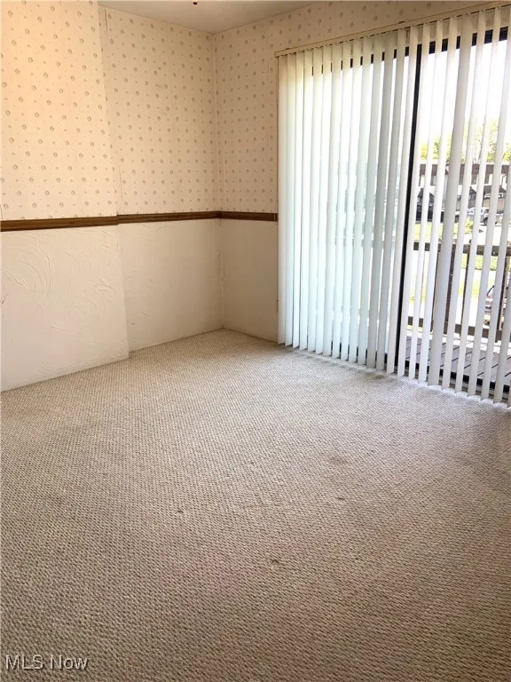 Spare room featuring carpet flooring and wallpapered walls