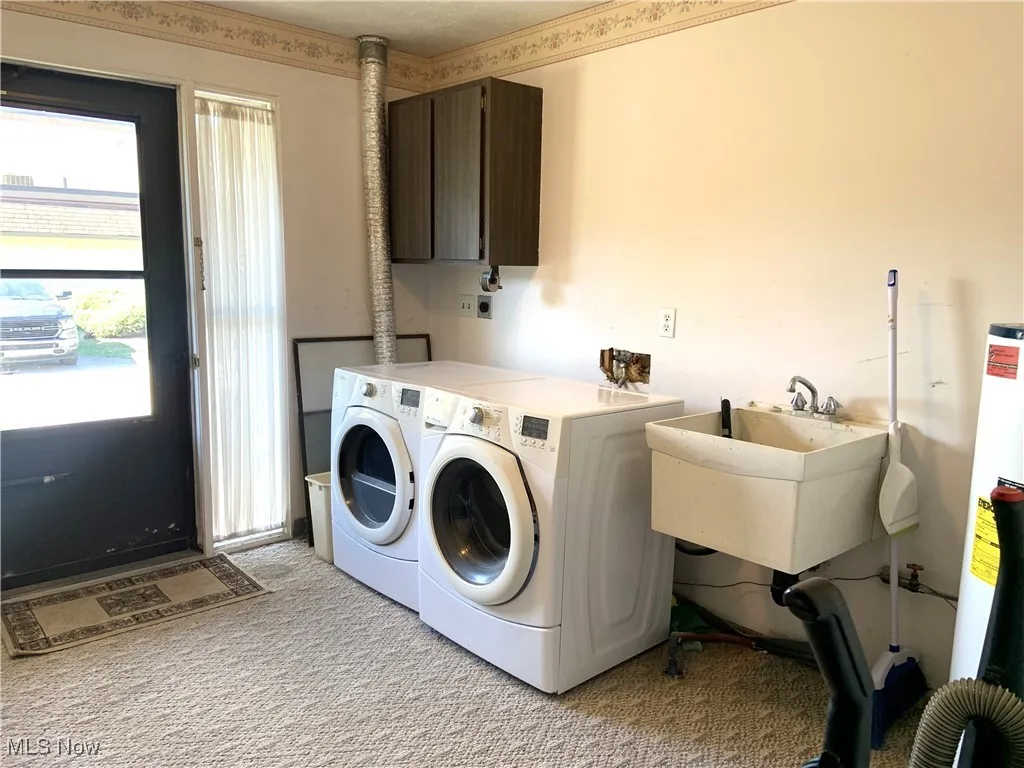 Laundry area with cabinet space, water heater, light carpet, and washing machine and clothes dryer