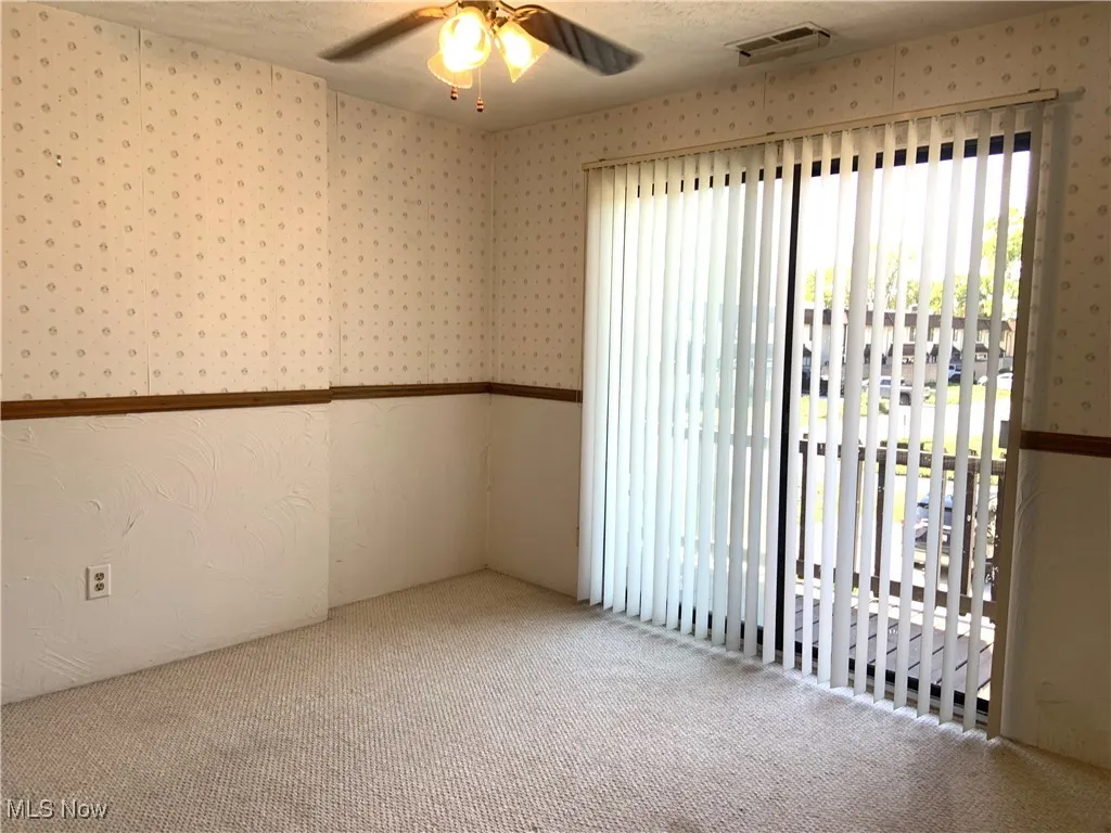 Carpeted empty room with a textured ceiling and a ceiling fan