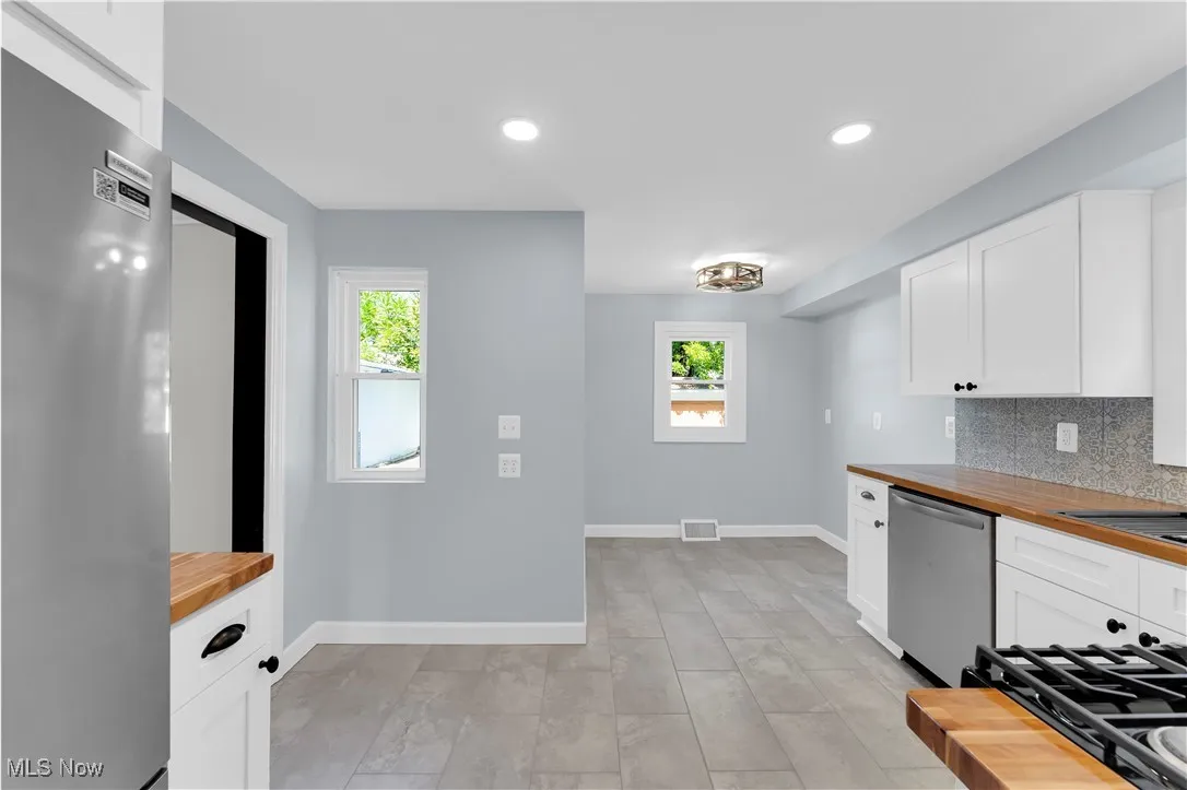 Kitchen with wood counters, white cabinetry, and recessed lighting