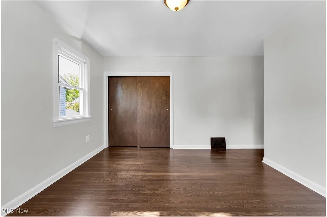 Unfurnished bedroom featuring a closet and dark wood finished floors