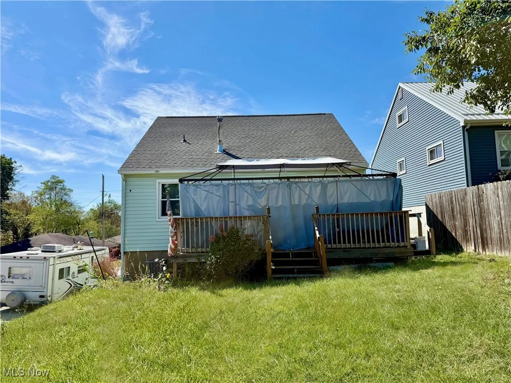 Rear view of house with a deck and a shingled roof