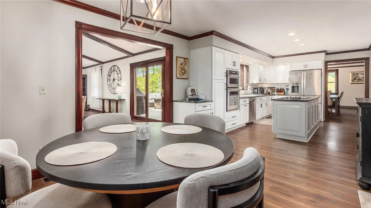 Dining room featuring dark wood-style flooring, healthy amount of natural light, ornamental molding, a chandelier, and recessed lighting