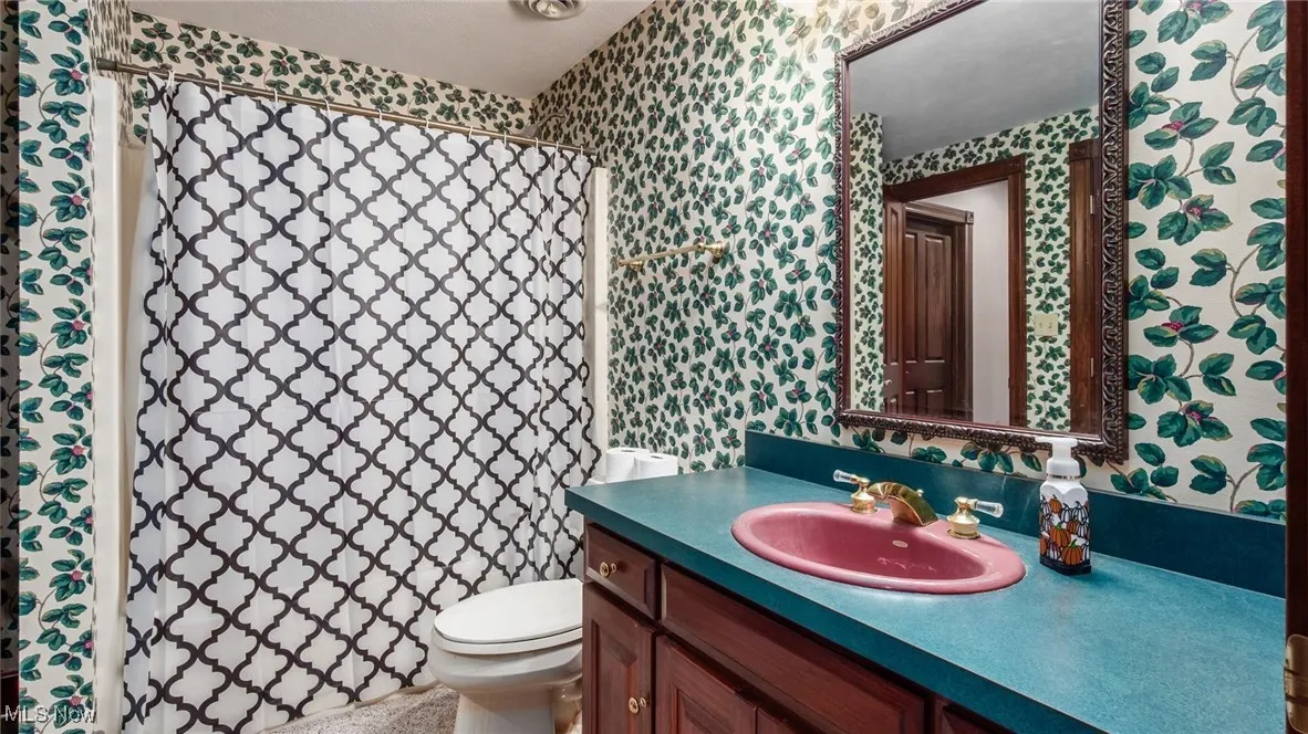 Bathroom with vanity, wallpapered walls, and a shower with curtain