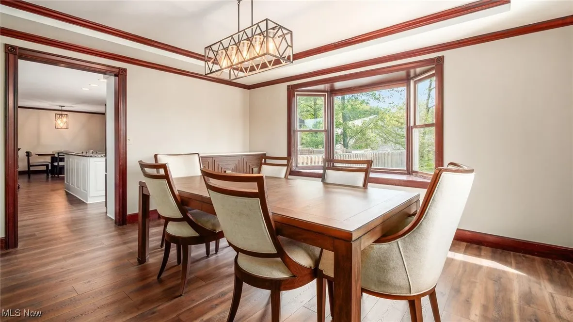 Dining room with ornamental molding, dark wood finished floors, and a raised ceiling