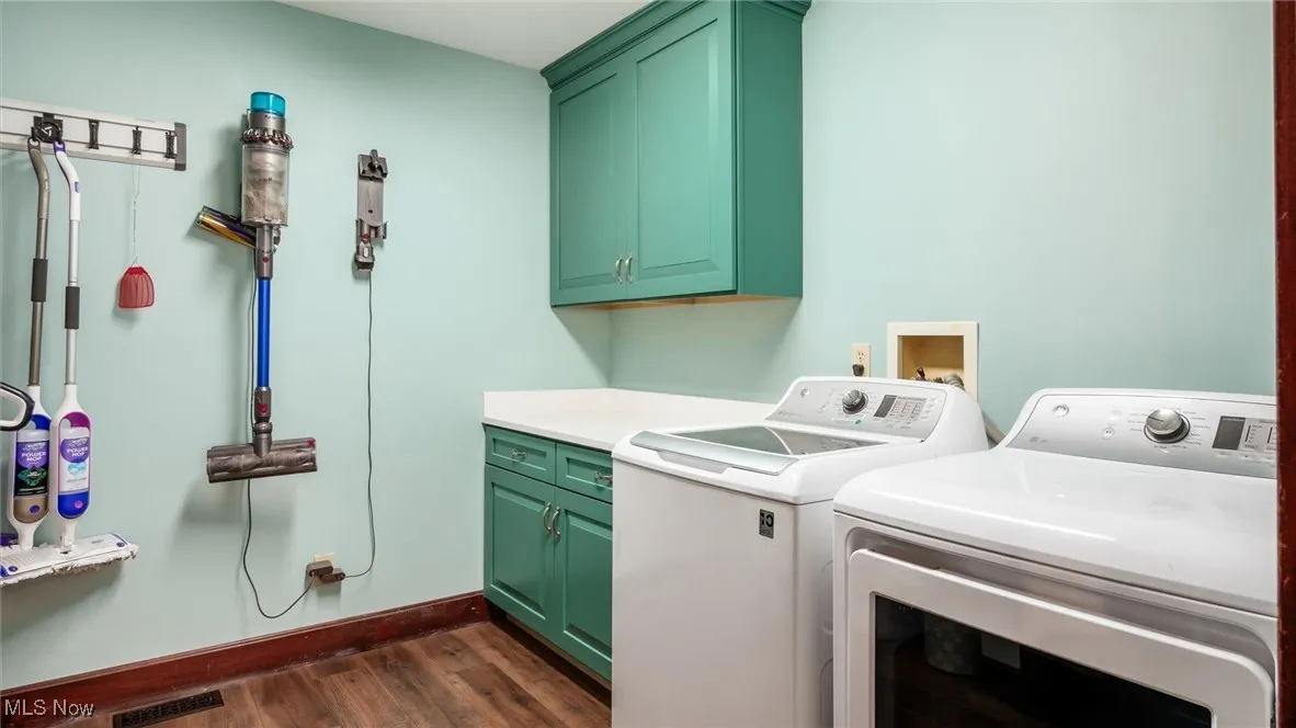 Laundry area featuring dark wood-style flooring, cabinet space, and washing machine and dryer