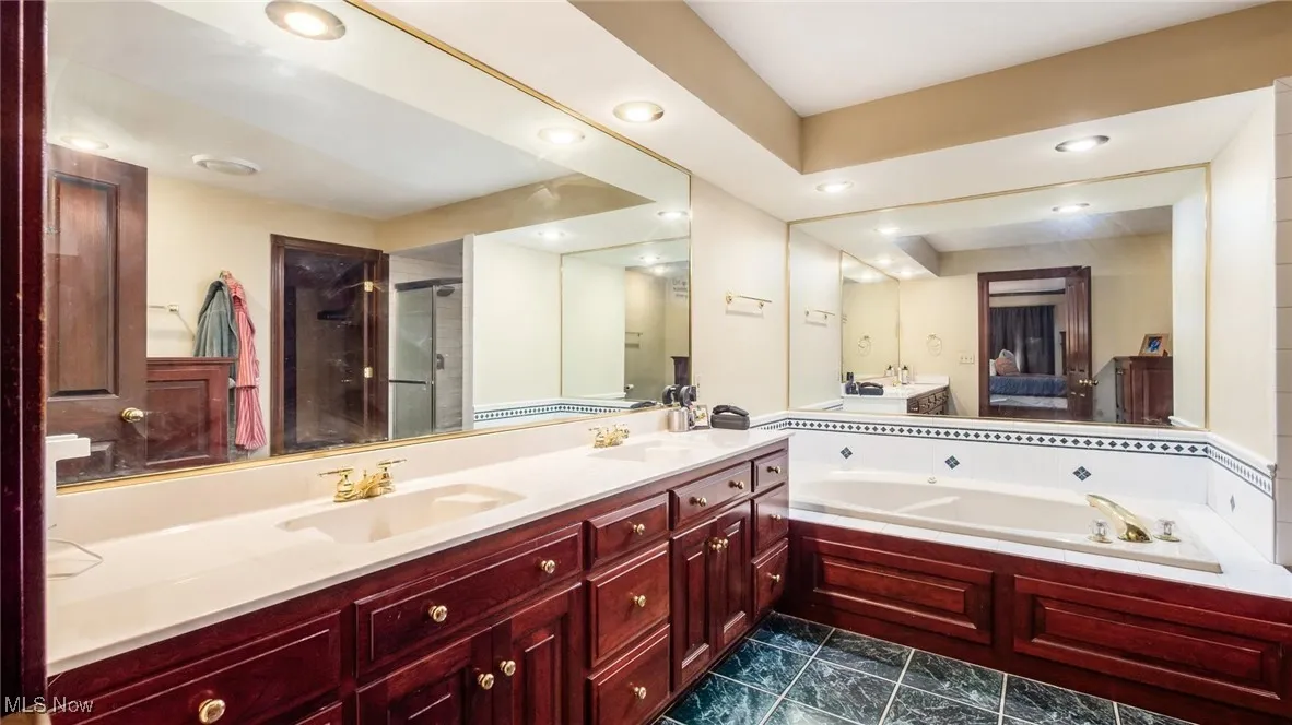 Full bath featuring connected bathroom, a bath, double vanity, a stall shower, and recessed lighting