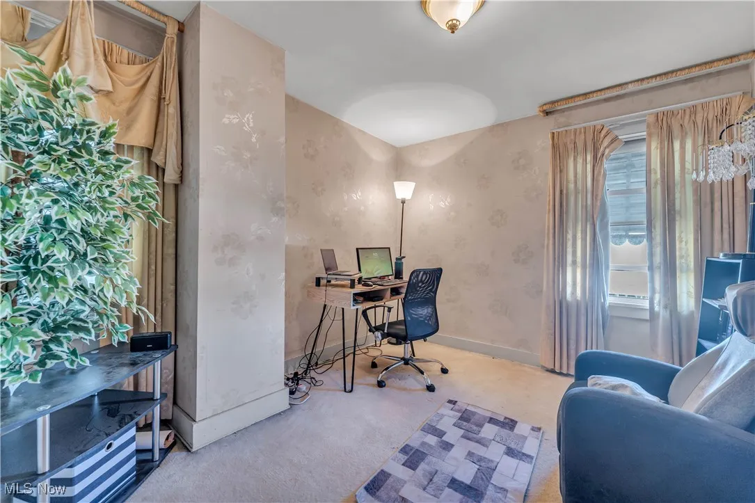 Office with light carpet and wallpapered walls