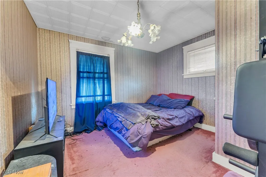 Carpeted bedroom with baseboards and a chandelier