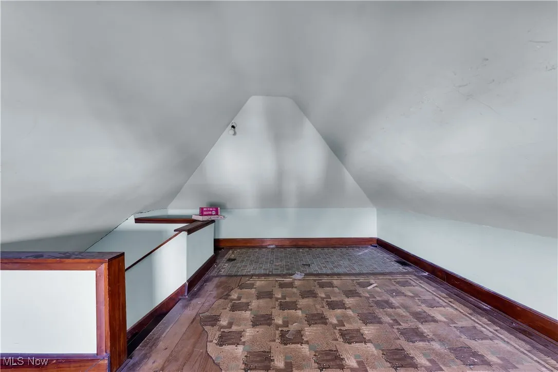 Additional living space featuring lofted ceiling and dark wood-style floors