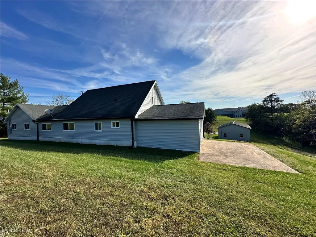 View of home's exterior featuring a lawn and roof with shingles