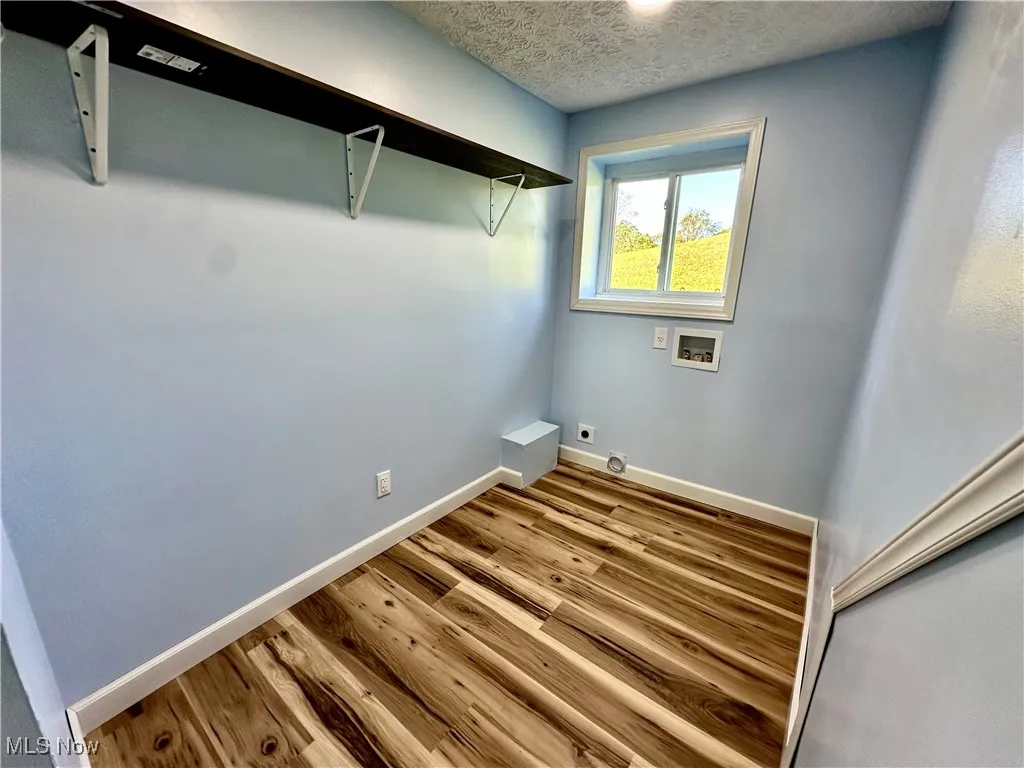 Washroom featuring a textured ceiling, hookup for a washing machine, wood finished floors, and electric dryer hookup