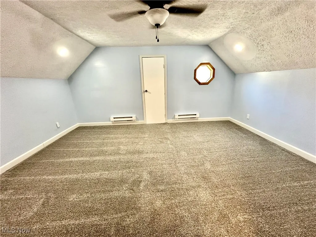 Bonus room with a textured ceiling, carpet flooring, lofted ceiling, and baseboard heating