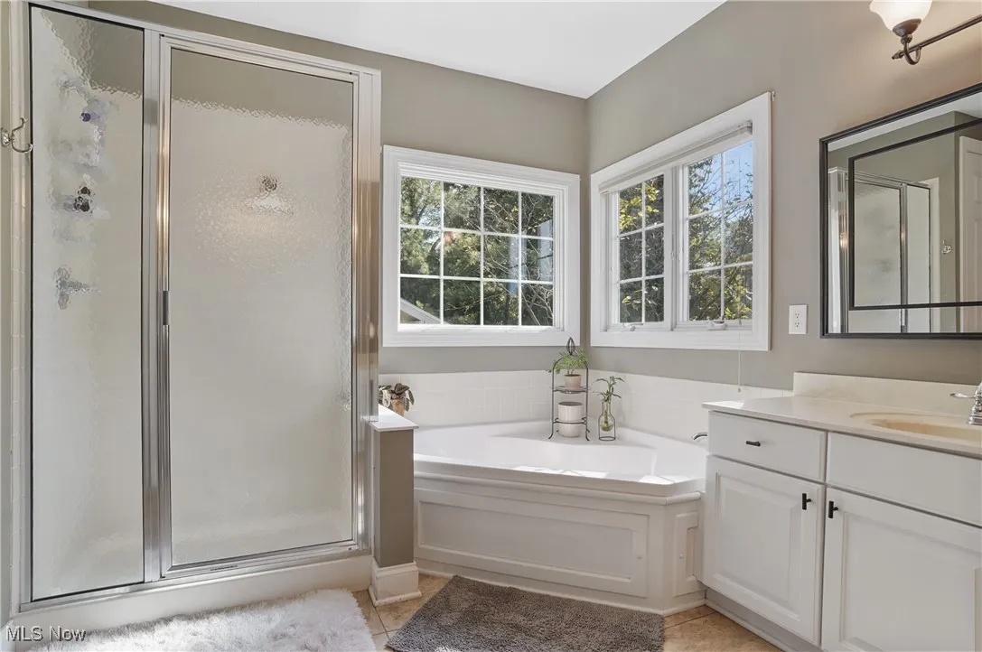 Full bathroom featuring a garden tub, vanity, a shower stall, and light tile patterned floors