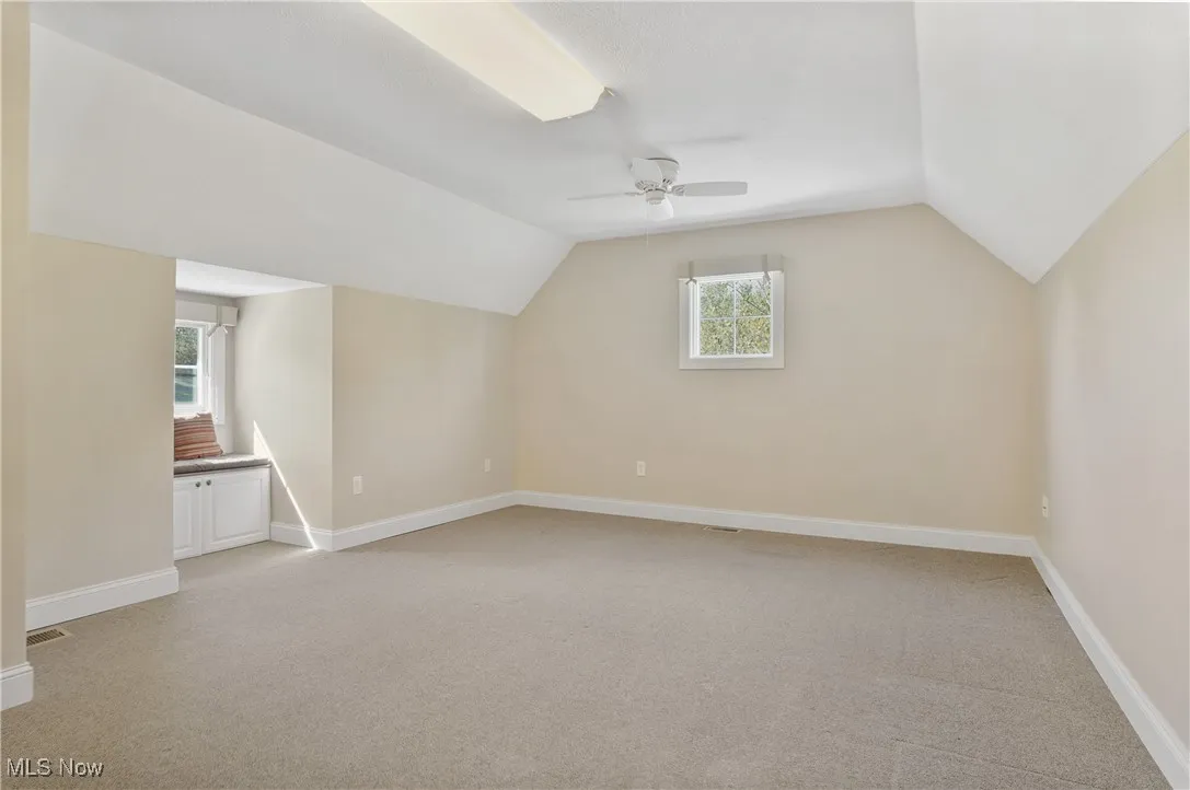 Additional living space with light colored carpet, lofted ceiling, plenty of natural light, and ceiling fan