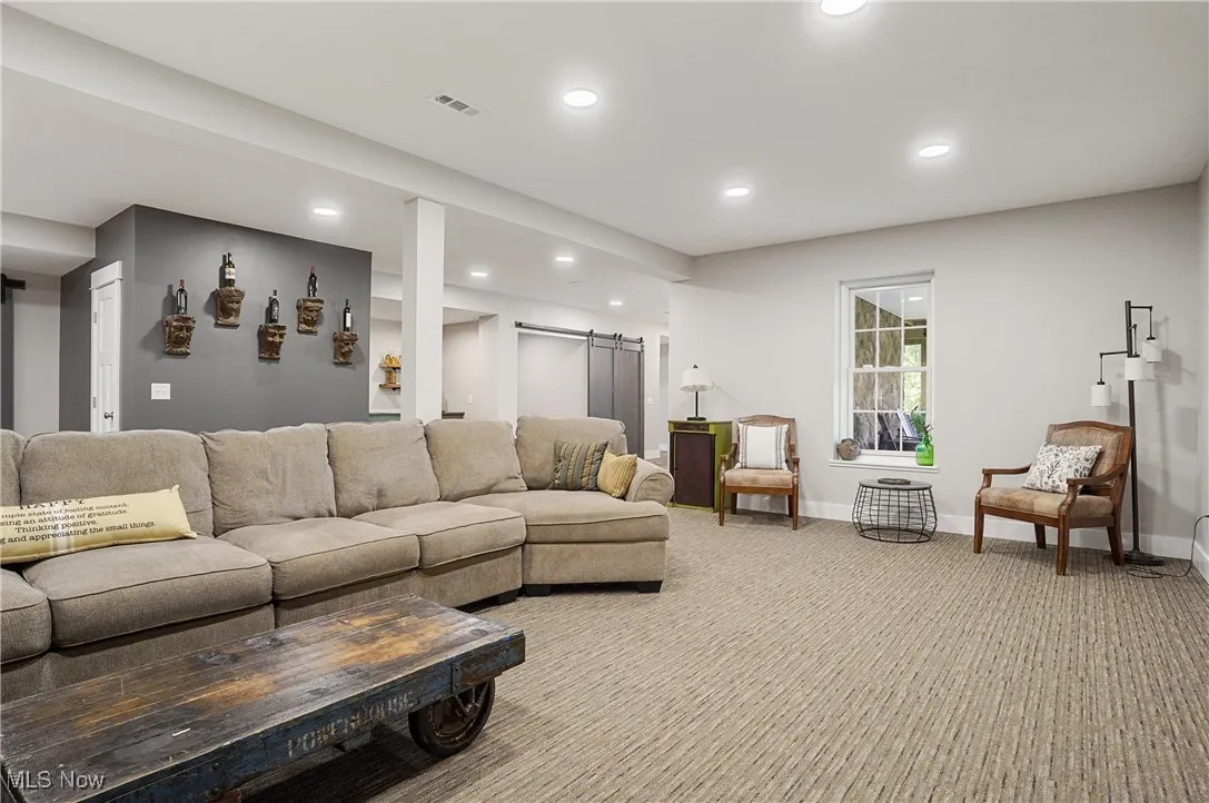 Living area with a barn door, recessed lighting, and light colored carpet