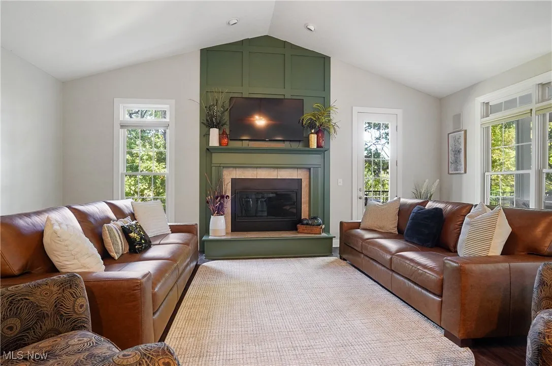 Living area featuring plenty of natural light, vaulted ceiling, a tiled fireplace, and wood finished floors