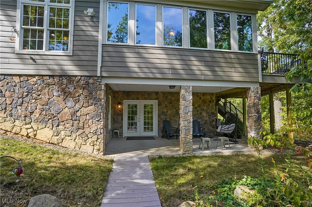 View of exterior entry featuring stone siding, a patio area, french doors, and a lawn