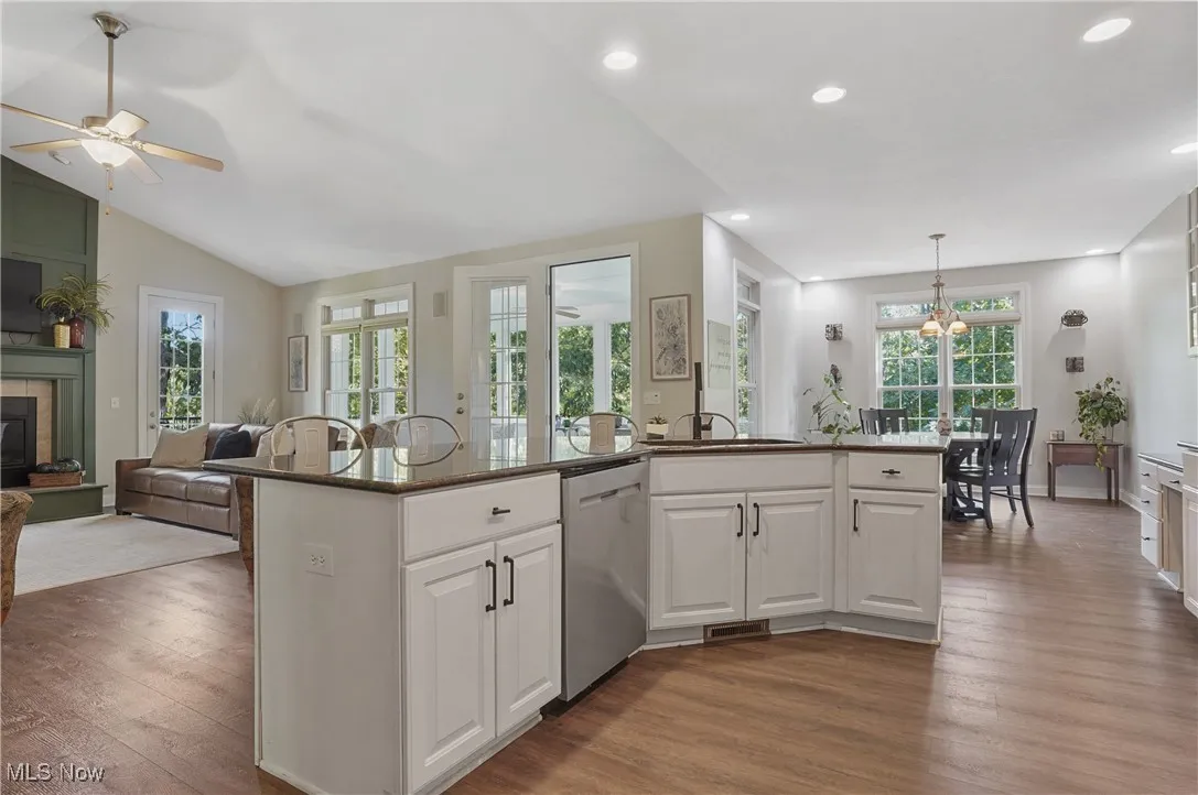 Kitchen with white cabinetry, open floor plan, recessed lighting, dark stone counters, and dark wood finished floors