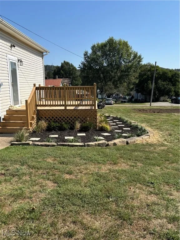 View of grassy yard featuring a deck