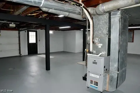 Below grade area featuring heating unit and electric panel