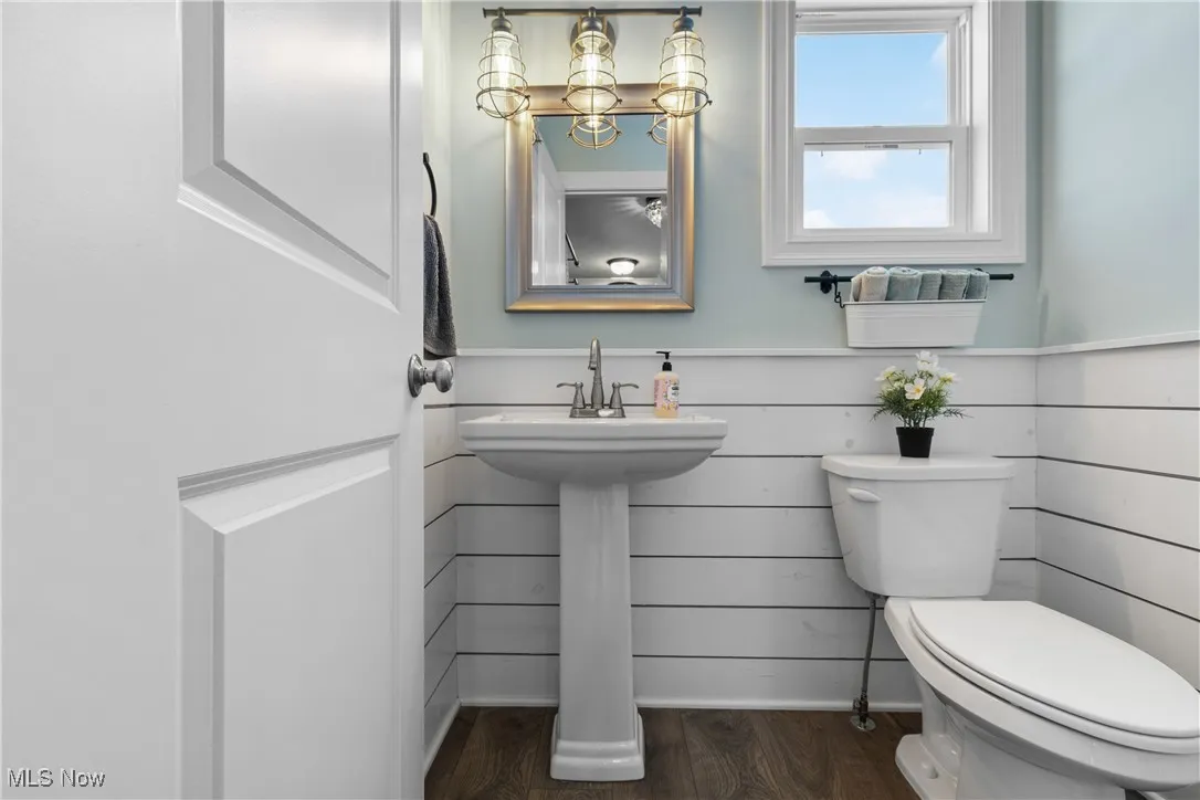Half bathroom featuring toilet and dark wood-style floors
