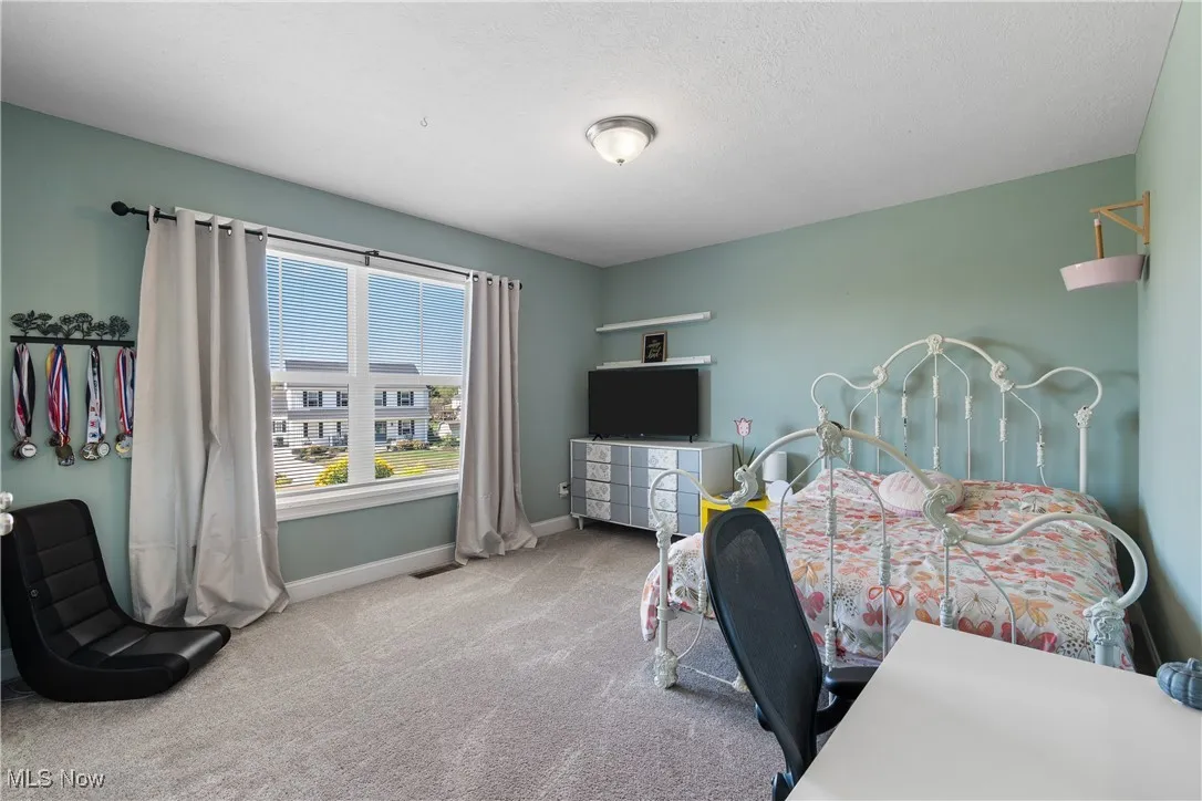 Carpeted bedroom featuring baseboards and a textured ceiling