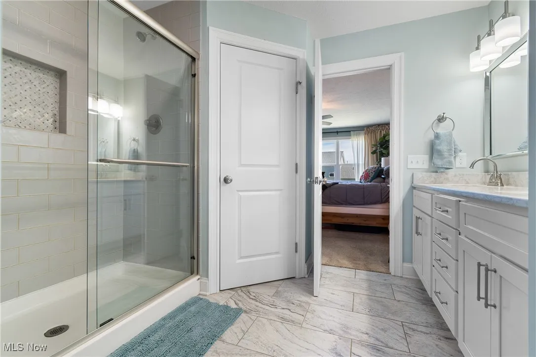 Full bath featuring vanity, a stall shower, and ensuite bathroom