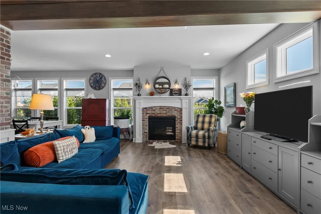 Living room with a fireplace, dark wood-type flooring, beamed ceiling, and recessed lighting
