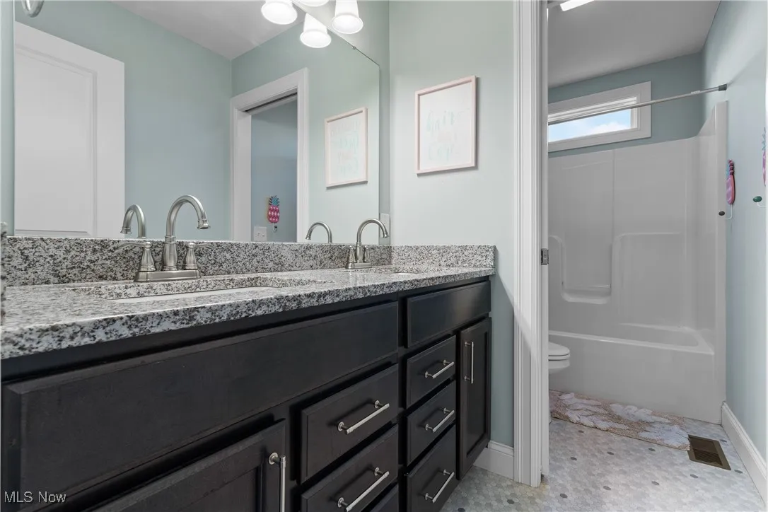 Bathroom featuring double vanity and shower / bath combination