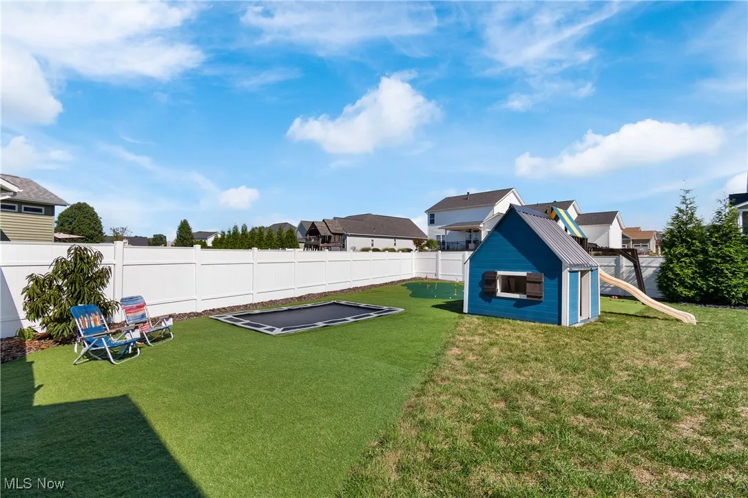 Fenced backyard featuring a playground