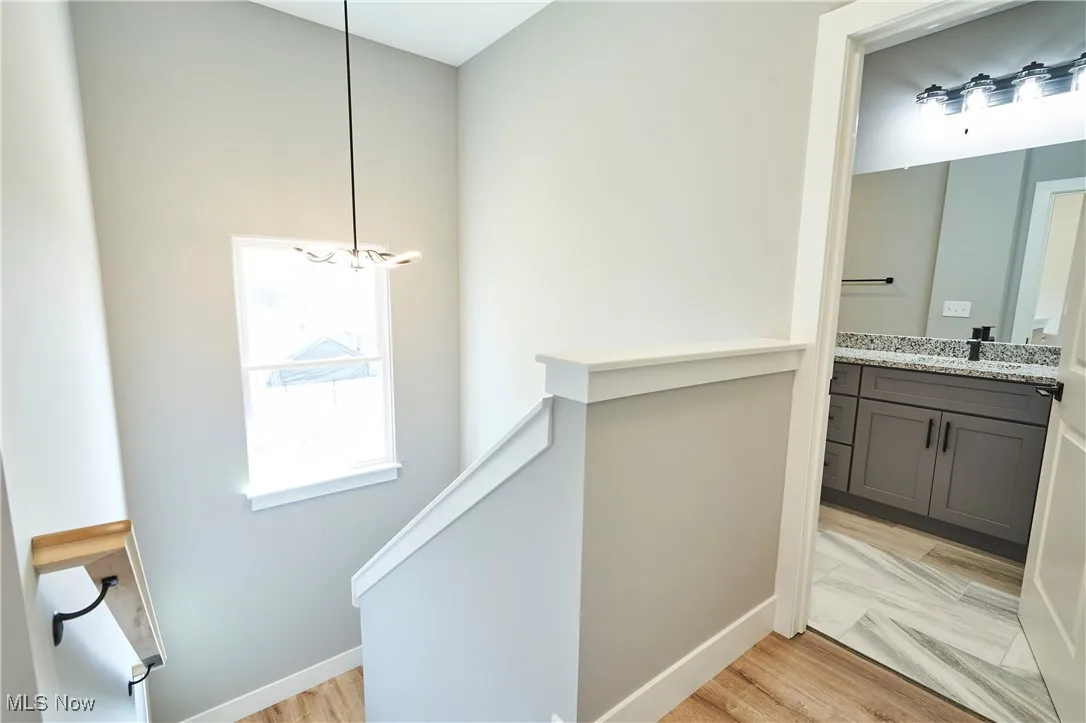 Hallway featuring light hardwood / wood-style floors, a notable chandelier, and sink