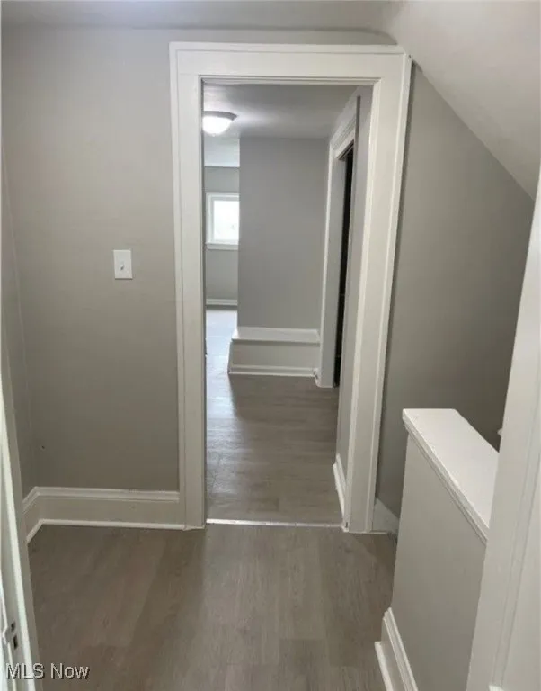 Corridor featuring dark wood-type flooring and baseboards