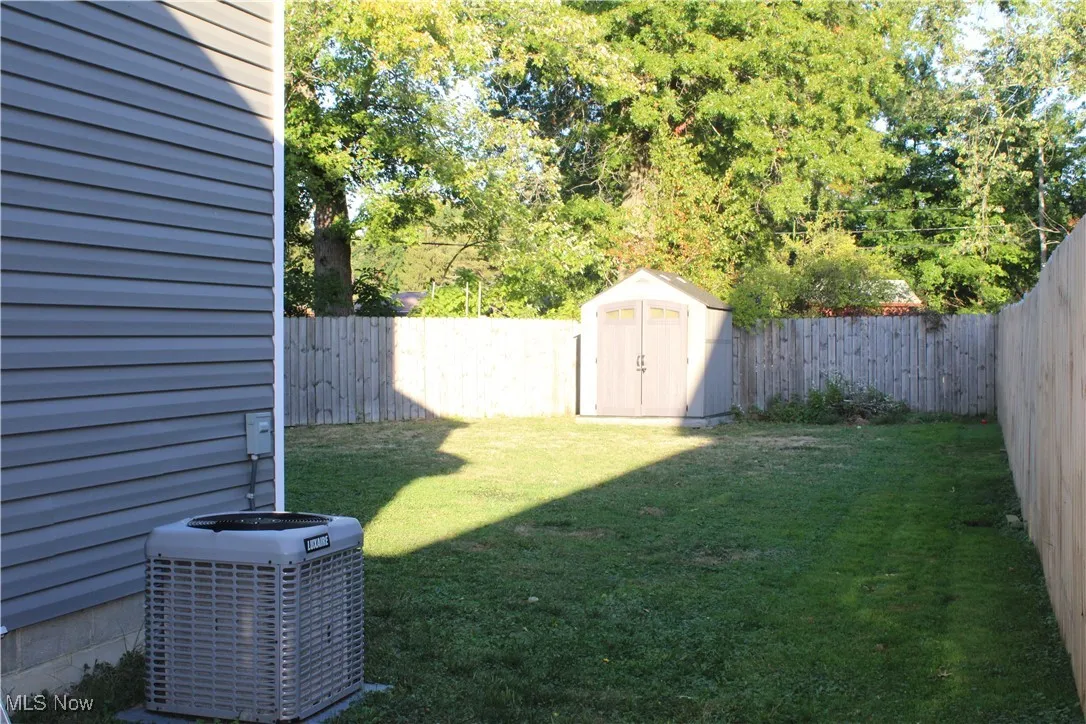 Fenced backyard featuring a shed