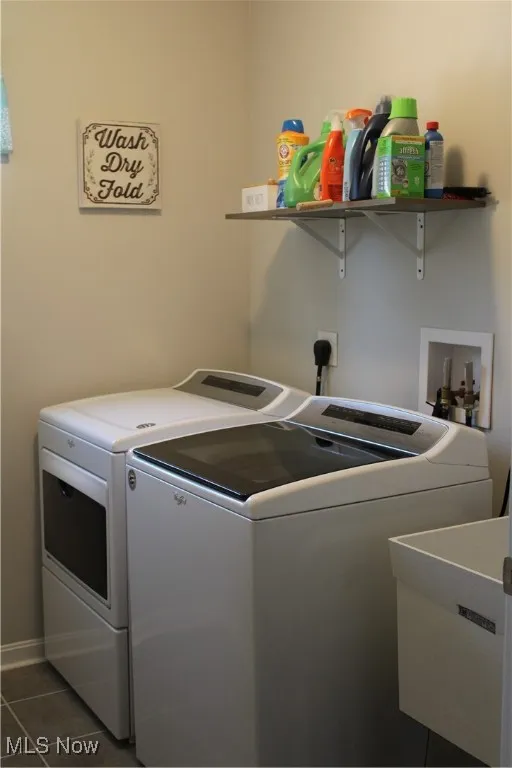 Laundry room featuring separate washer and dryer and dark tile patterned flooring