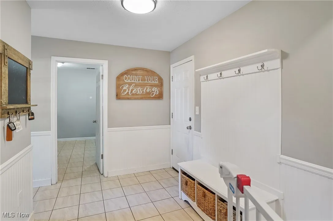 Mudroom with wainscoting and light tile patterned floors