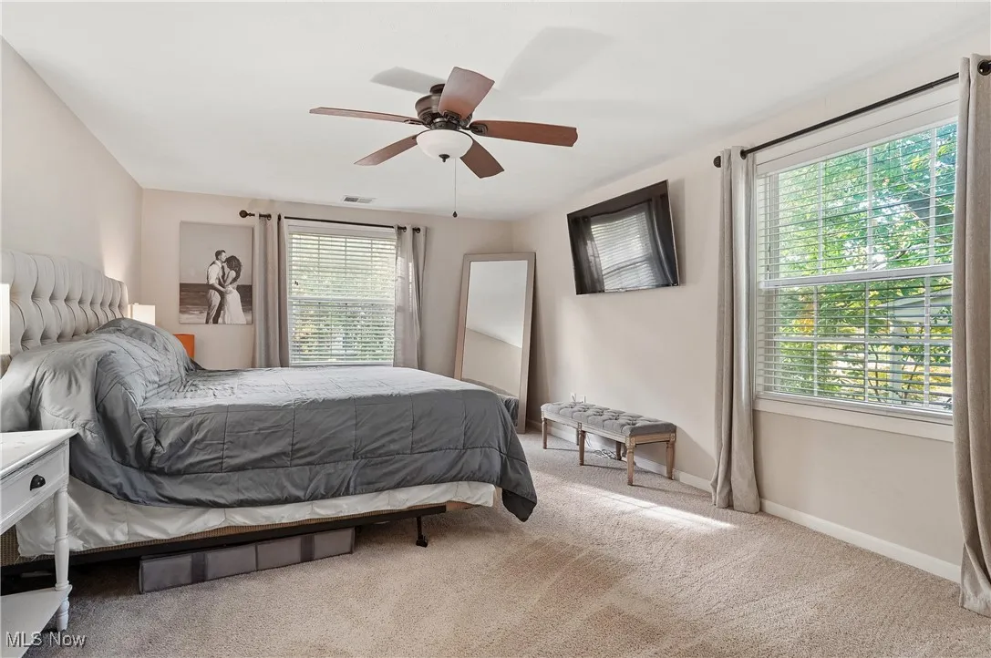 primary bedroom with light colored carpet and a ceiling fan