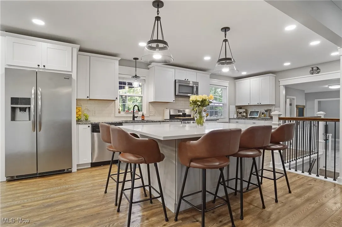 Kitchen with a kitchen island, stainless steel appliances, light wood lvt flooring, pendant lighting, and recessed lighting